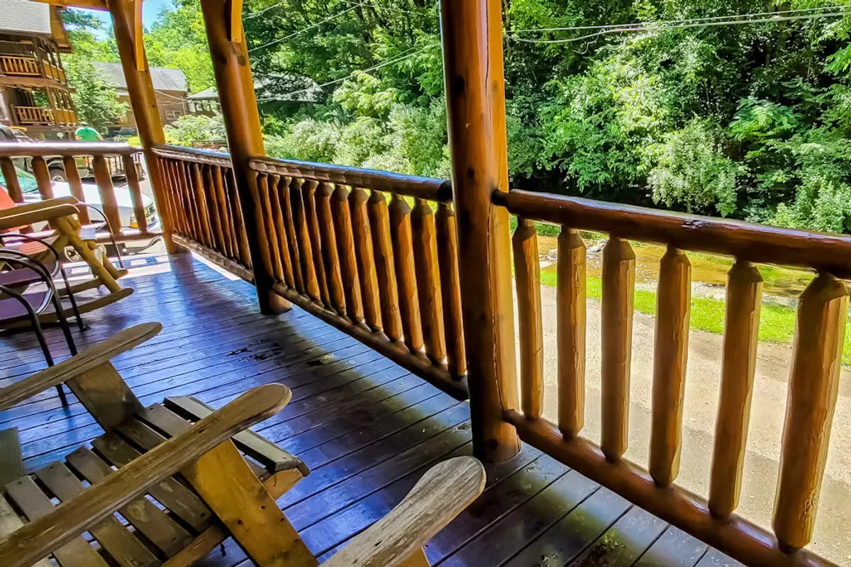 This exterior image captures a wooden porch with classic rocking chairs overlooking a lush, green landscape. The scene exudes tranquility and offers a perfect vantage point for relaxing while immersed in nature.