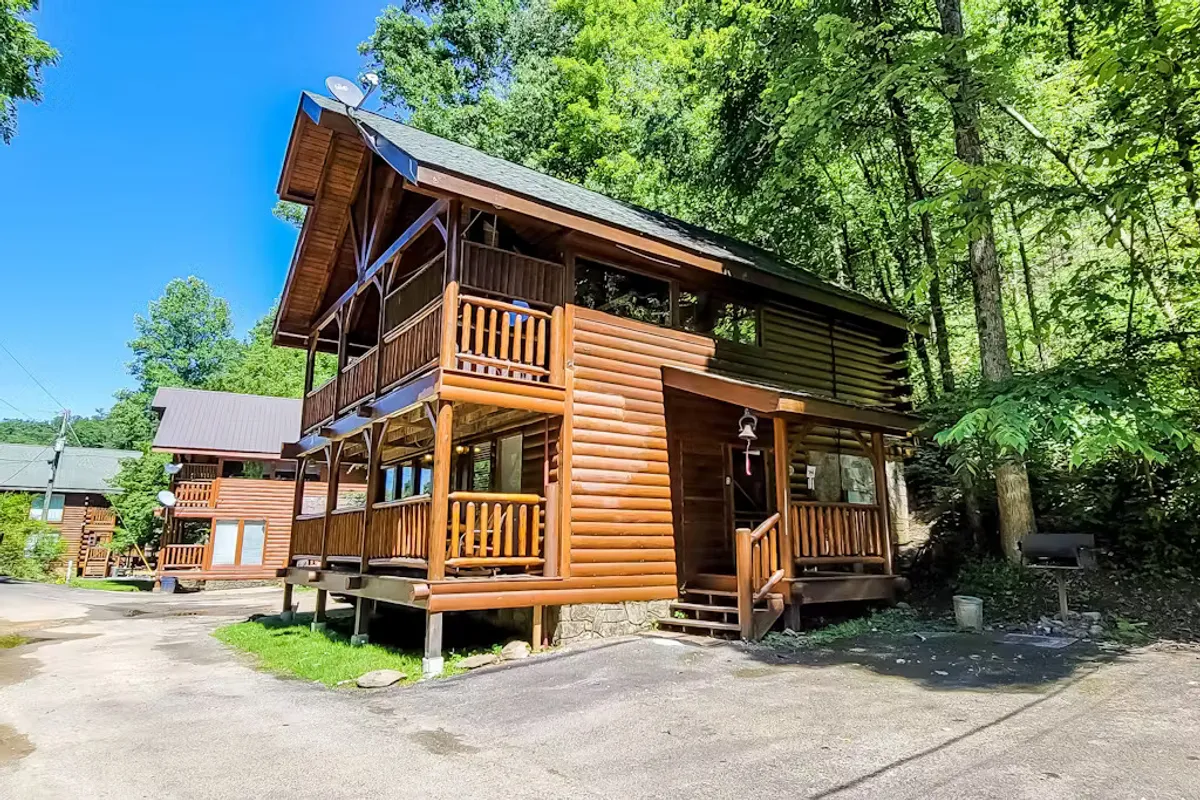 A classic log cabin with spacious balconies is nestled among lush greenery. The inviting exterior hints at the adventures awaiting both outside and within, with balconies perfect for morning coffee or evening gatherings surrounded by nature.